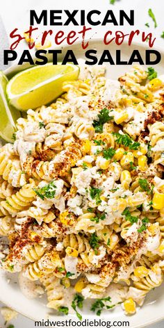 mexican street corn pasta salad in a white bowl with lime wedges on the side