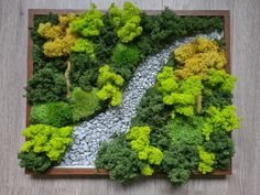 an aerial view of a river surrounded by green trees and rocks in a wood frame