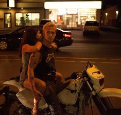 a man and woman sitting on the back of a motorcycle