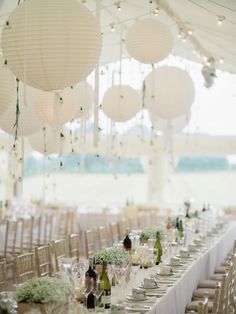 the tables are set up with white paper lanterns hanging from the ceiling and vases filled with flowers