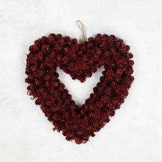 a heart made out of red flowers on a white surface with a string attached to it