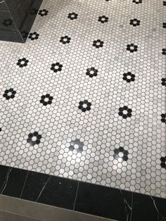 a black and white tiled bathroom with hexagonal tiles on the floor, along with an open shower stall