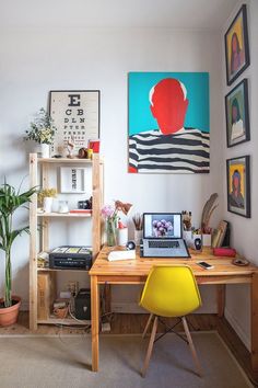 a desk with a laptop on top of it next to a potted plant and bookshelf