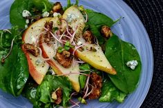 a blue plate topped with spinach, apples and other food on top of it