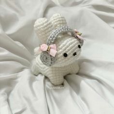 a crocheted white stuffed animal with a pink bow on it's head