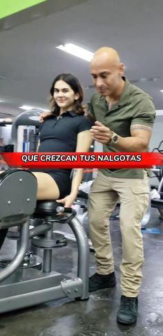 a man standing next to a woman on top of a bench in front of a gym machine