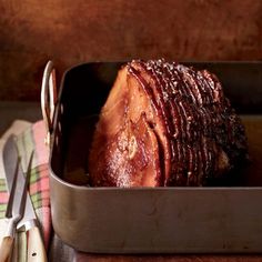 a large piece of meat sitting in a pan on top of a table next to utensils