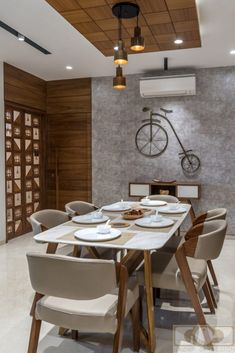 a dining table with chairs and plates on it in front of a bike mounted to the wall