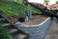 a man standing on top of a pile of dirt next to a stone wall and steps