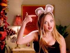 a woman in a black top is posing with her hand up to the side while wearing bunny ears