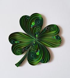 a green four leaf clover with swirls on it's back and the petals are shaped like spirals