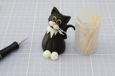 a black and white cat figurine next to a cup with straws in it