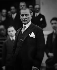 a man in a suit and bow tie standing next to other men