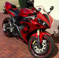 a red motorcycle parked on top of a brick sidewalk