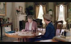 two women sitting at a table with cookies on it