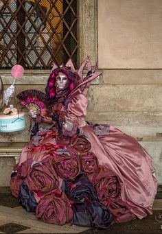 a woman in a pink dress sitting on a bench next to a cake and fan