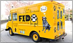 a yellow food truck parked on the side of the road with a dog's paw painted on it