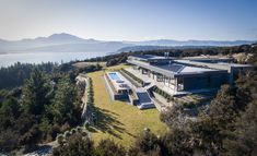 an aerial view of a large house in the middle of some trees and water with mountains in the background