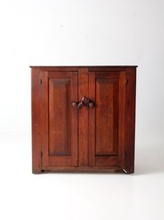 an old wooden cabinet with two doors and knobs on the front, against a white background