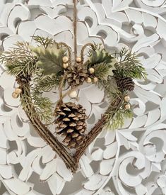 a heart shaped ornament with pine cones and greenery hanging from it's sides