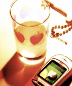 a cell phone sitting on top of a table next to a glass filled with liquid