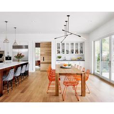 an open kitchen and dining room with white walls, wood flooring and large windows