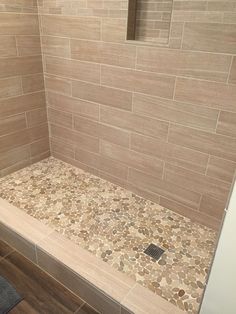 a walk in shower sitting next to a wooden floor and tiled back splash on the wall