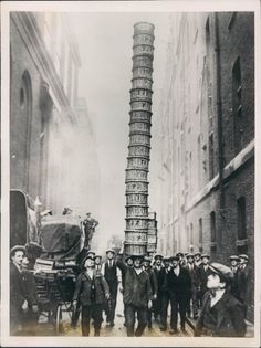 a group of men standing next to each other in front of a tall tower with many people around it