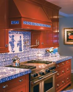 a kitchen with red cabinets and blue tile backsplash