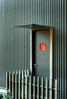 an open door with a red painting on it in front of a metal wall and fence