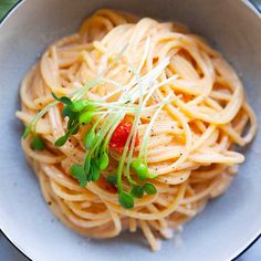 a white bowl filled with pasta and garnished with parsley on the side