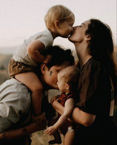 a woman kissing her two children while they are surrounded by other women and babys