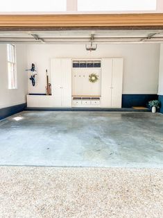 an empty garage with white cabinets and blue carpeting on the floor in front of two windows