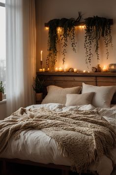 an unmade bed with candles and plants on the headboard