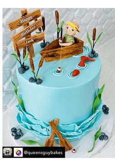 there is a blue cake with an image of a boy in a boat on it