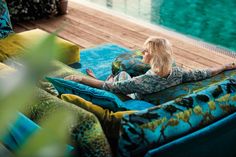 a woman sitting on top of a couch next to a pool