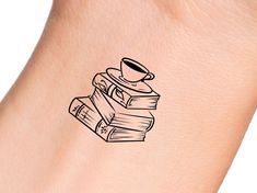 a tattoo with books and a cup on it