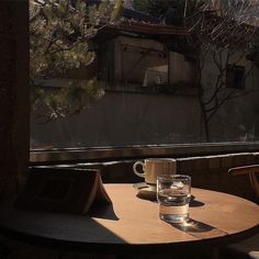 two empty cups sit on a table in front of an open window