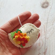 a hand holding a small felt ornament with flowers on it's face