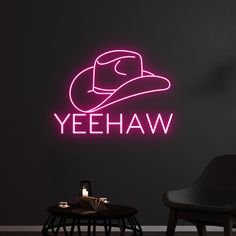 a neon sign that says yeehaw on the wall next to a chair and table