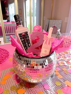 a disco ball centerpiece with pink and gold confetti on the table in front of it