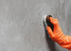 a person in orange gloves scrubbing a wall