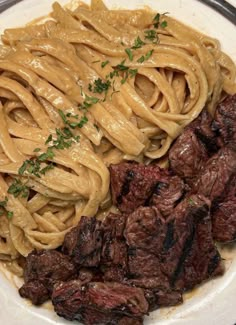 a white plate topped with pasta and meat next to sauce on top of it's side