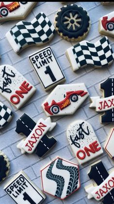 decorated cookies with race cars and numbers are displayed on a brick wall in front of a sign that says speed limit