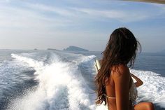 a woman sitting on the back of a boat in the ocean