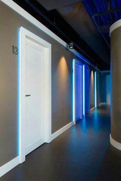 an empty room with two doors and blue lights on the wall behind it is a round light fixture