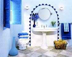 a white sink sitting under a bathroom mirror next to a blue vase filled with flowers