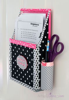 a black and white polka dot pocket with pink trim on the side, holding pens and scissors