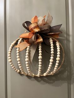 a wooden beaded wreath hanging on a door with a ribbon attached to the front