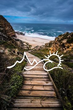 a wooden path leading to the beach with mountains in the distance and waves crashing on top